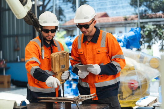 Two robotic technician discussing review welding robot testing welding before delivery, supporting inspection, programming, calibration, safety, quality assurance, commissioning.