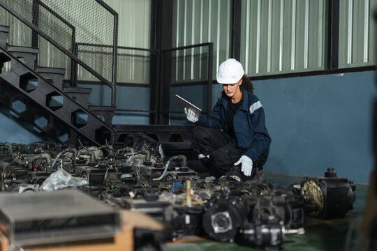 Female industrial technician check industrial robotics spare parts with tablet in warehouse. supporting inventory check, spare parts audit, management.
