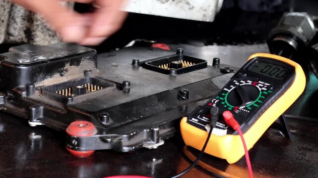 Professional automotive technician checking and diagnosing electronic control unit module using digital multimeter.