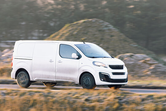 White cargo van driving on rural road
