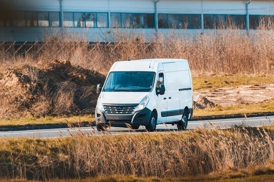 White commercial van driving past green countryside