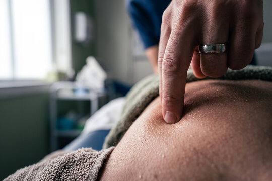 Close-up of a finger pressing on a person's back during a massage