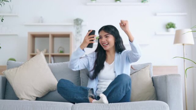 Happy young asian woman relax on comfortable couch at home texting messaging on smartphone, smiling girl use cellphone, chatting online message, shopping online from home