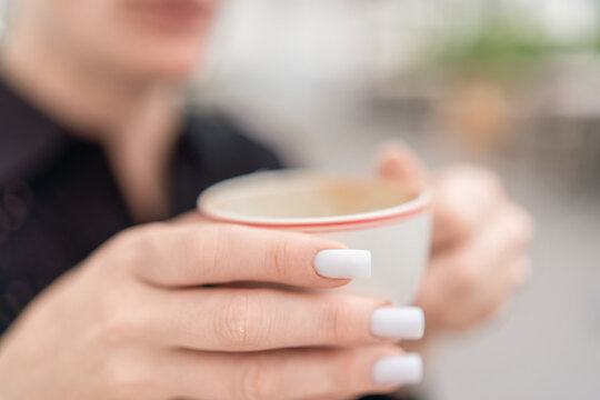 Manicured nails woman holding white ceramic coffee cup during quiet morning break indoors
