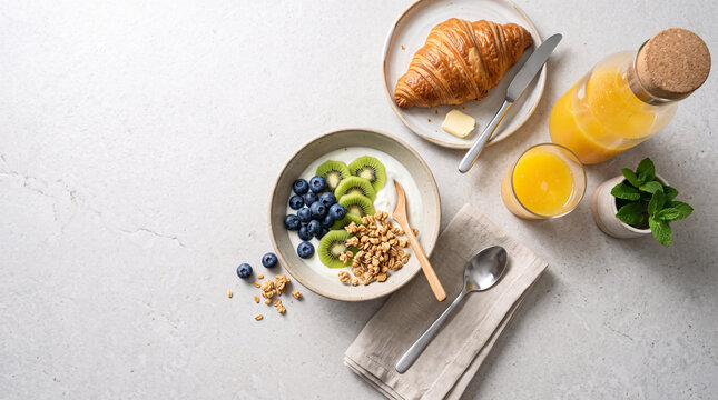 Petit d&eacute;jeuner sain avec yaourt, fruits, granola et jus d&rsquo;orange