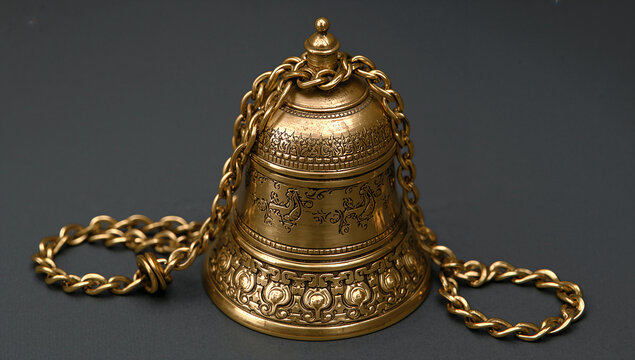 Vintage ornate brass hand bell with decorative metal chain decorative handbell instrument craftsmanship traditional ceremonial collectible engraved ornament artifact ornamental metalwork