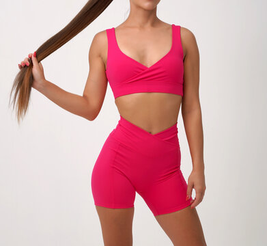 Athletic woman wearing bright pink sports bra and fitted workout shorts 