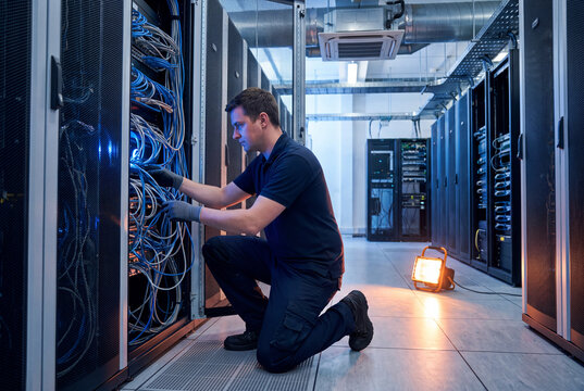 Data center technician organizing cables on server rack storage room cabinet management information technology worker full body specialist staff cloud
