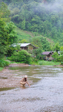 A woman touching and playing with water in the river in rural village