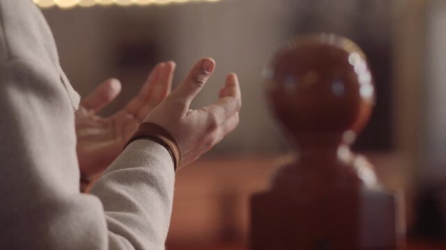 A young woman stands with hands raised in prayer inside of a mosque .