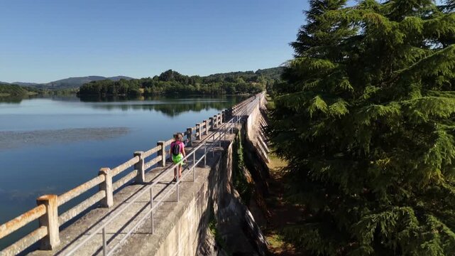 Aerial drone descending crane shot revealing bridge footpath beside calm lake