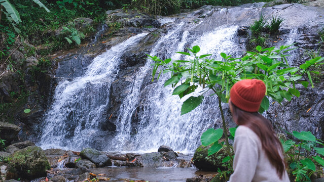 A woman sitting and relaxing by the waterfall in the forest
