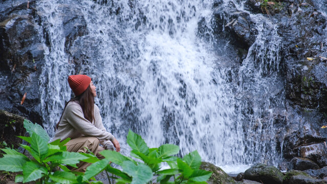 A woman sitting and relaxing by the waterfall in the forest