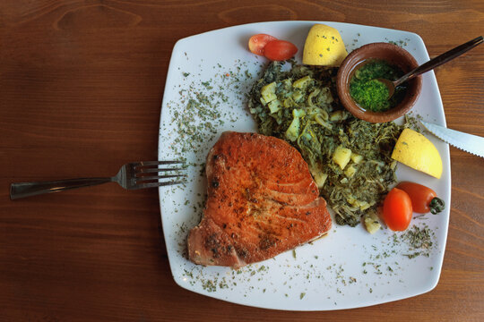 Balkan cuisine. Grilled tuna steak  with green leafy vegetables. Copy space