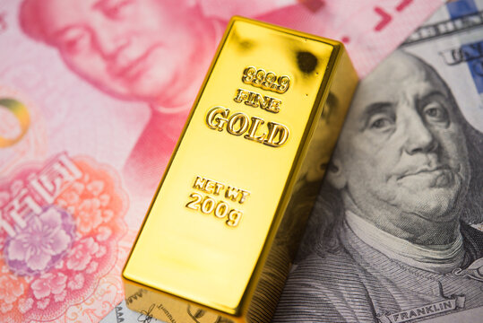 Gold bar on US dollar and Chinese yuan bill banknote. Central bank of US America and China keeps gold reserves, gold price increase, global finance and commodity trading market investment concept.