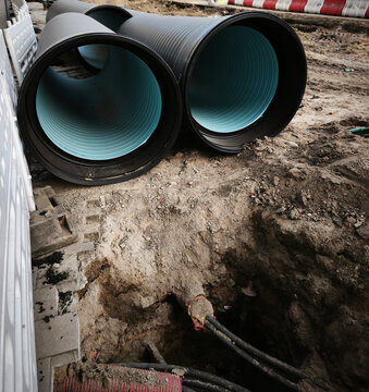 Big construction site. Excavated urban trench with manhole and paved surroundings