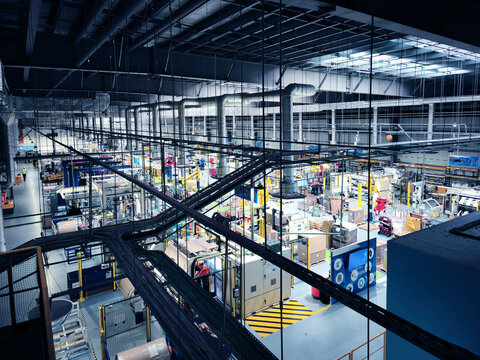 Overhead view of busy exhibition hall with illuminated booths, technicians inspecting displays.