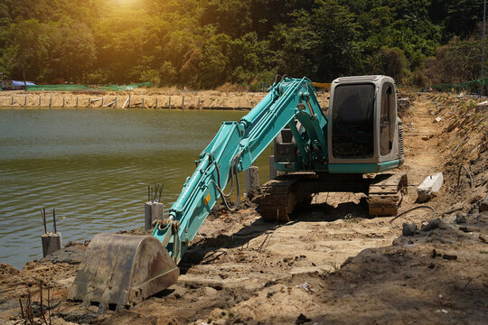 Building process city levee. Excavator dredging pond bank