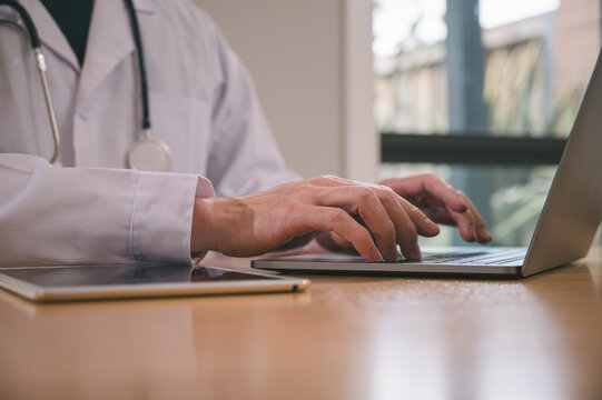 Male doctor wearing white cloth using stethoscope tablet and computer working diagram analysing patient diagnosis data with virtual heart icon in medicine and healthcare concept