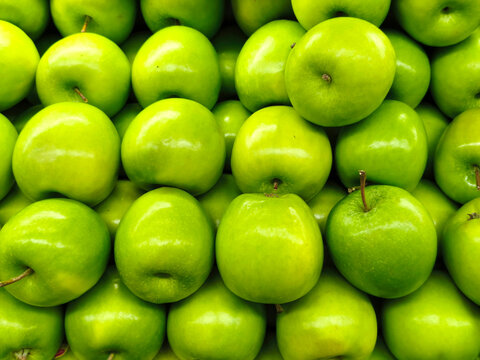 Fresh green apples pile background full frame macro shot of glossy granny smith apples