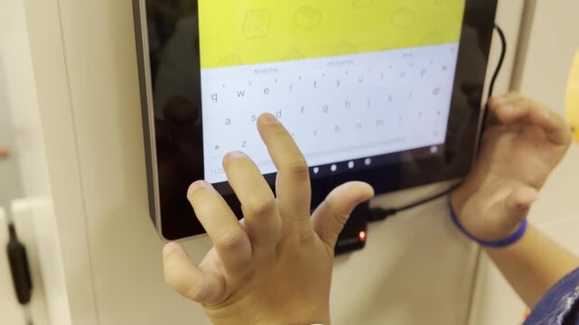 Child using a tablet touchscreen keyboard, tapping and typing on a digital device indoors.