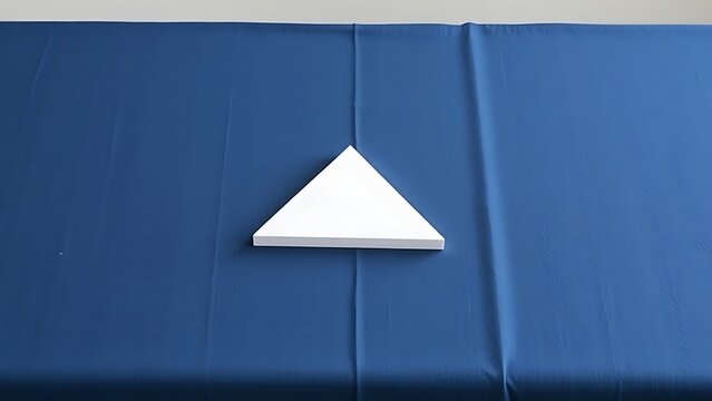 equilateral. Single white equilateral triangle object on deep blue linen, calm still life for editorial concept, lifestyle magazines.