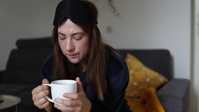 Young woman hesitates with a cup of coffee wondering if she can resist another sip after deciding to give up caffeine for the sake of her health and wellbeing