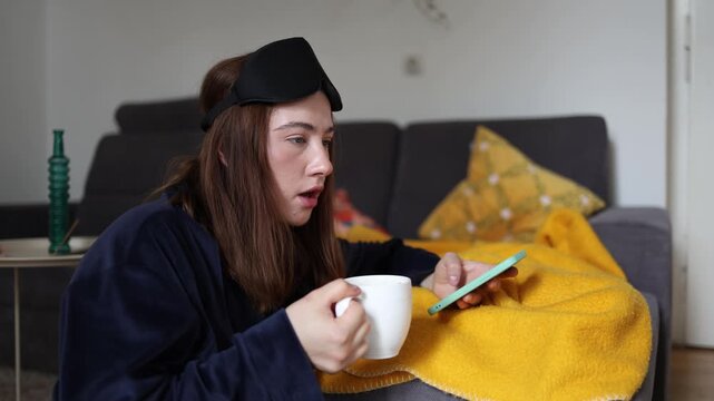 Coffee and social media have become a fast morning dopamine routine as a young woman checks her phone before fully waking up and starting the day mindfully