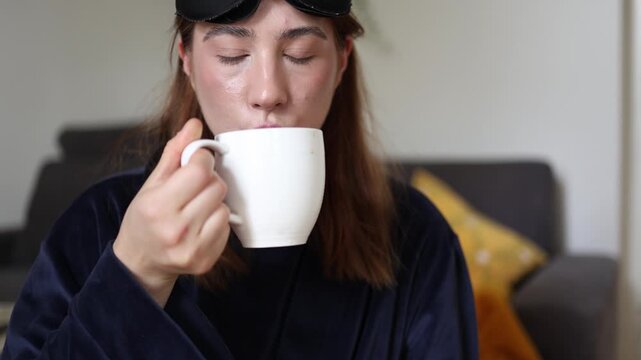 Coffee arrives just in time as a sleepy young woman reaches for a warm cup from someone nearby making the first sip feel like the start of a more awake morning