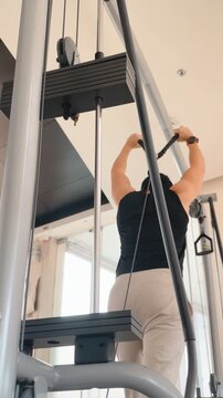 Adult Person Exercising Triceps on a Cable Machine in a Modern Gym Setting