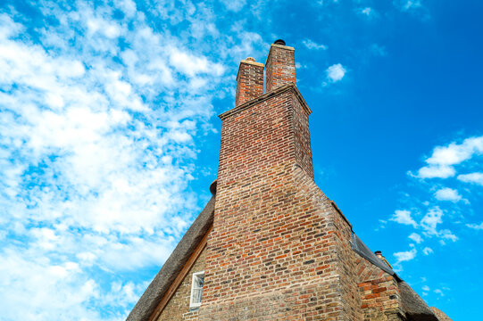 Detailed view of a very old, brick built English cottage which has recently been renovated. Showing the cleaned bricks and pointing leading to a tall, double chimney.