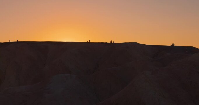 Silhouetted People Walking Along Ridge at Zabriskie Point Sunset, Death Valley