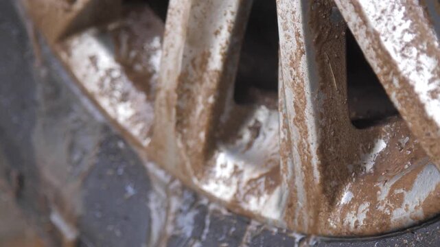 Slow motion close up footage of a muddy car wheel after off road driving. For off road, vehicle maintenance, adventure, dirt, rugged transportation, and automotive concepts
