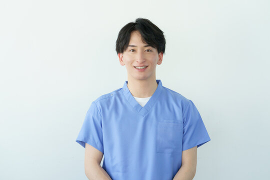 白背景のスクラブを着た若い日本人男性整体師