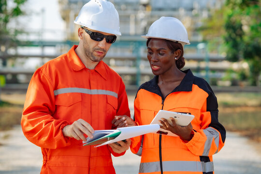 Industrial maintenance professionals reviewing operational documents and digital reports at processing plant. Engineering inspection, equipment reliability, technical assessment and industrial safety.
