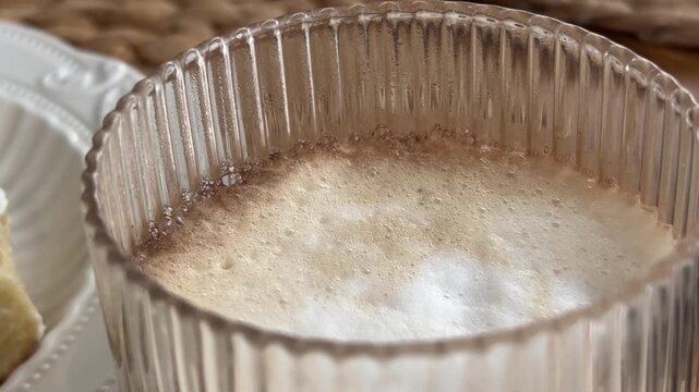 Cup of warm frothy coffee served with sweet dessert pastries on a table, cozy morning breakfast lifestyle concept