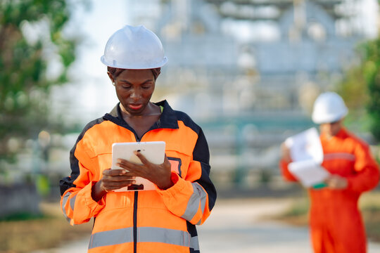 Field engineer using digital tablet to inspect industrial processing plant. Maintenance monitoring, engineering analysis, workplace safety, technical inspection and operational efficiency.