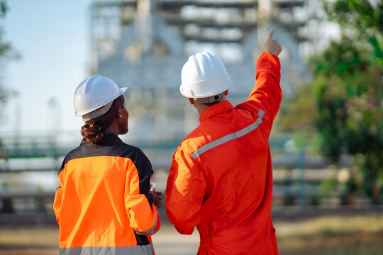 Industrial engineers reviewing refinery equipment while discussing maintenance priorities. Technical inspection, engineering collaboration, safety planning, asset management and process optimization.