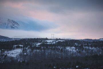 Obraz premium Winter view of power lines crossing snowy forest near Malangen Fjord in Troms, Northern Norway