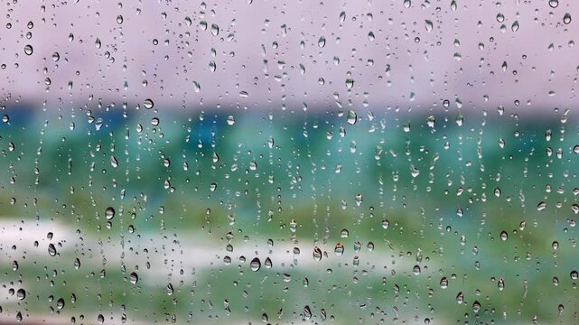 Close-up view of raindrops sliding down window with Atlantic Ocean waves in background. Miami Beach. USA.