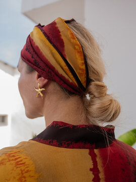 Luxury satin head wrap with tropical sunset print styled with elegant low bun and statement earrings