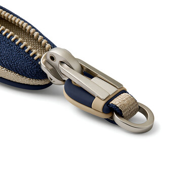 Close-up of a metallic zipper slider with a blue fabric pull tab on a