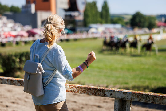 Woman cheering favorite horse during race. Excited spectator supporting horse racing competitor