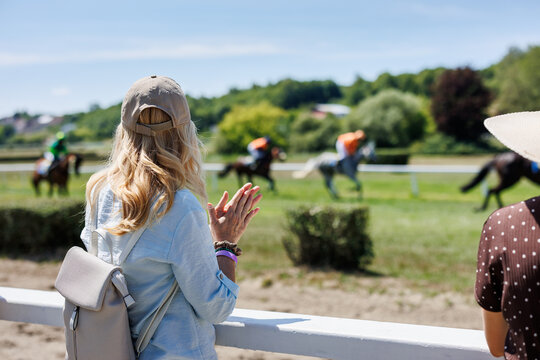 Woman spectator applauding winning racehorse after horse race finish