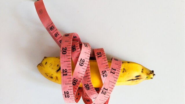 measuring tape with yellow banana isolated on white