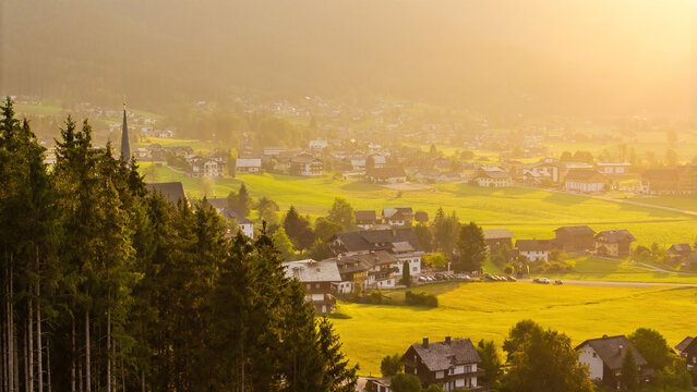 Alpine green fields, church and traditional wooden houses view of the Gosau village at summer sunny morning.