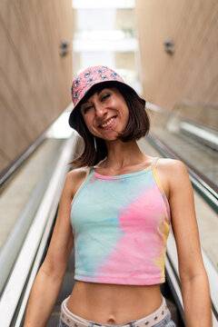 A portrait of a beautiful young woman outdoors. She is wearing colorful clothing and is smiling and laughing.