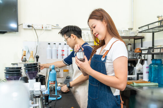 Small business entrepreneur coffee shop cafe restaurant. Asian woman barista using manual espresso maker making freshly brewed coffee on bar counter. Waitress serving beverage drink to customer.