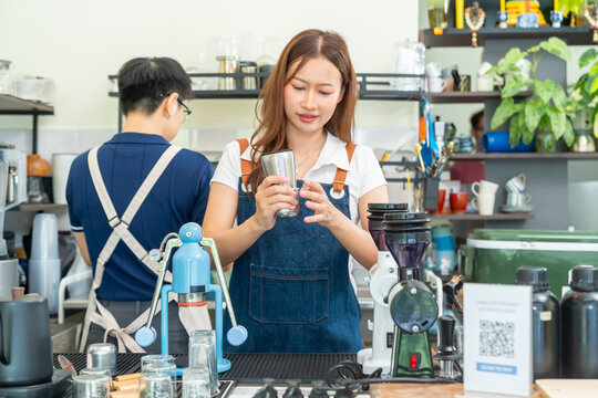 Small business entrepreneur coffee shop cafe restaurant. Asian woman barista using manual espresso maker making freshly brewed coffee on bar counter. Waitress serving beverage drink to customer.