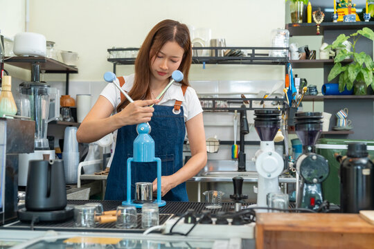 Small business entrepreneur coffee shop cafe restaurant. Asian woman barista using manual espresso maker making freshly brewed coffee on bar counter. Waitress serving beverage drink to customer.